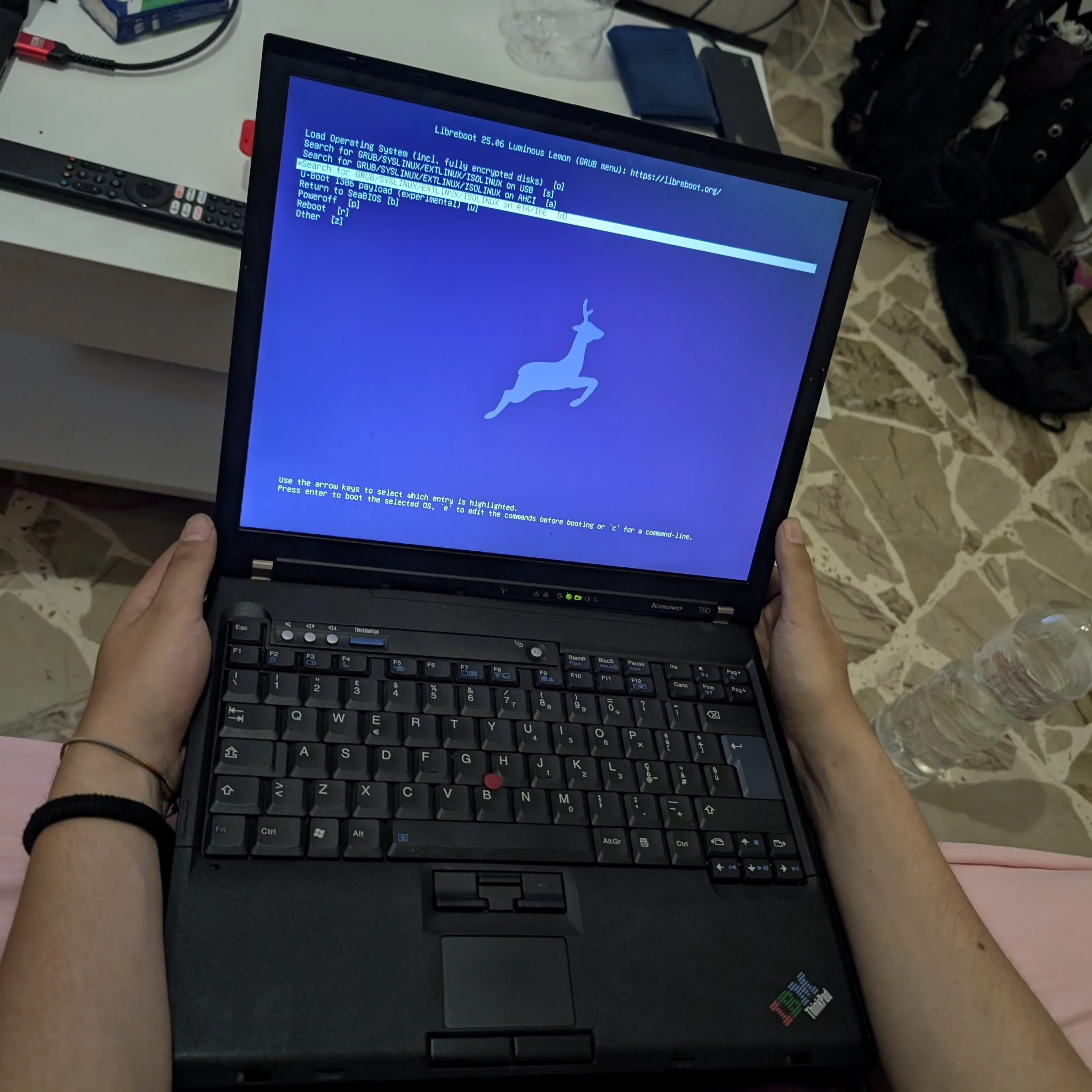 The T60 shown reassembled and booting into the Libreboot GRUB menu.